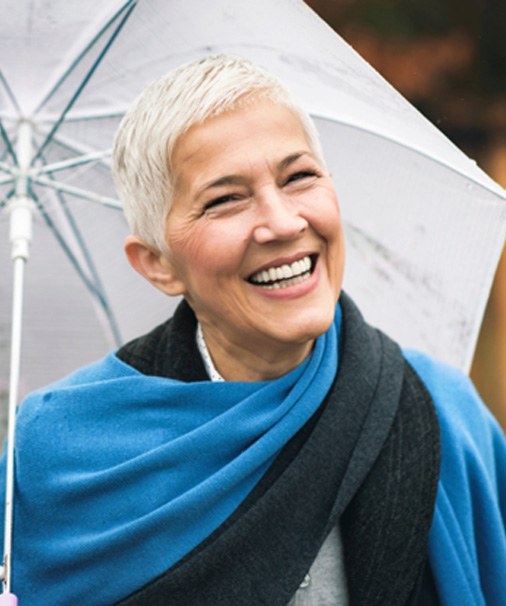 Senior woman outside smiling with umbrella