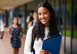 Teenage girl smiling while holding blue binder
