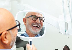 Happy dental patient’s face reflected in mirror