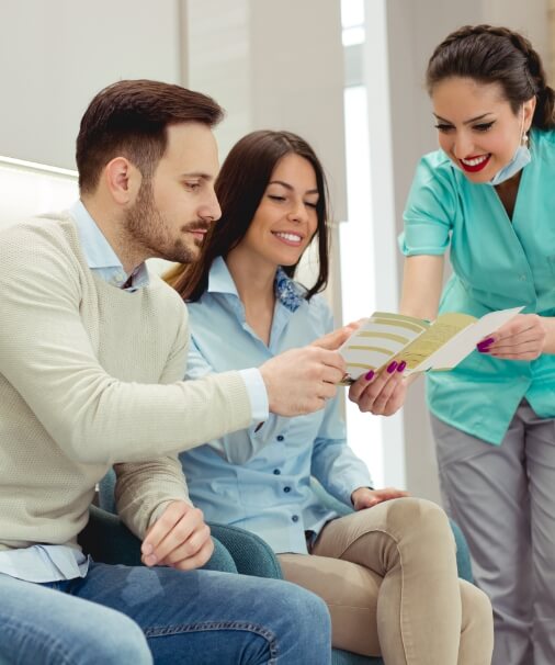 Dental team member and patients reviewing dental insurance information