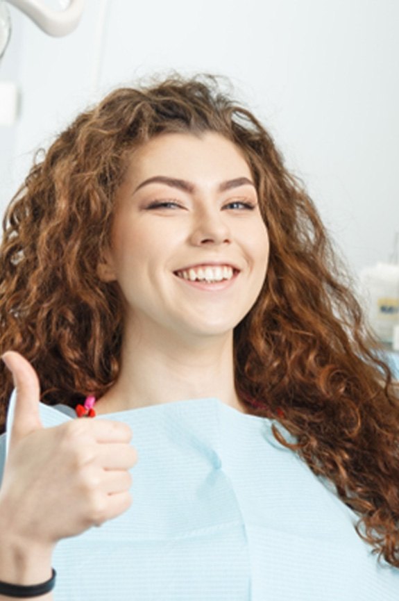 Female dental patient giving a thumbs up