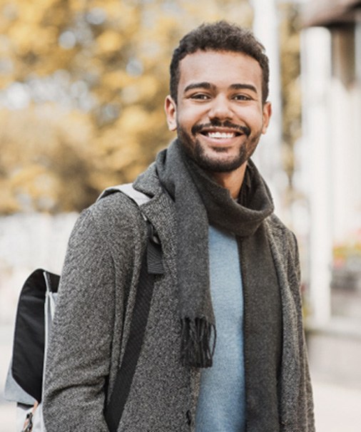 : Man in scarf walking outside and smiling
