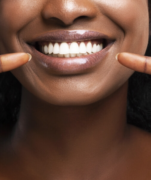 Patient pointing to smile after teeth whitening