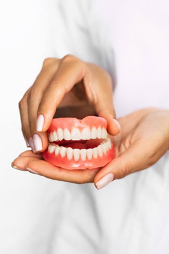 Dental professional holding full dentures in Newbury Park, CA