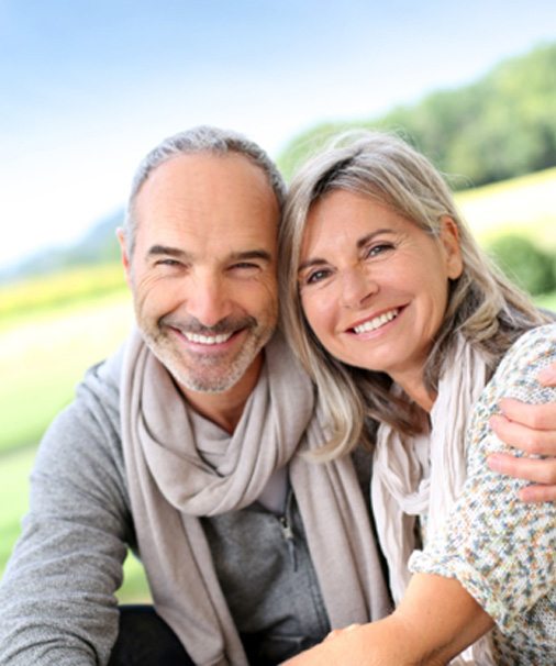 Senior man hugging senior woman while sitting outside