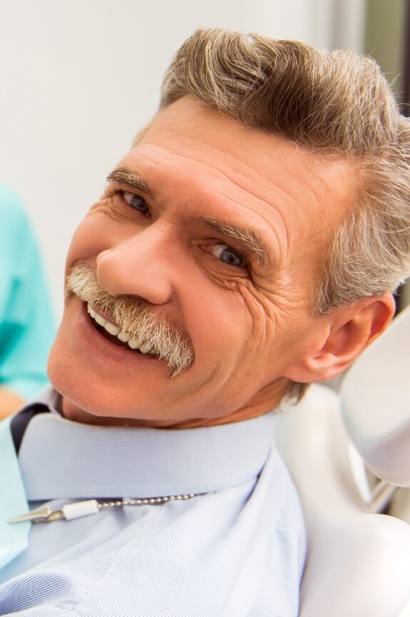 Smiling man with dentures at dental appointment