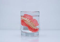 Dentures soak in glass of water