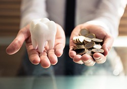 Man holding a tooth and a pile of coins