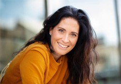 Woman in orange sweater smiling outside