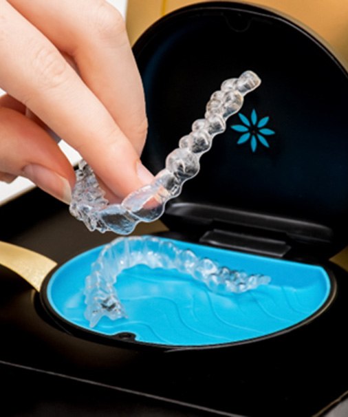 A woman putting Invisalign trays in a case