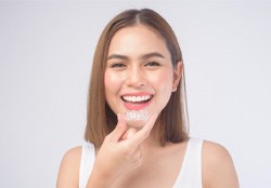 A woman with a straight smile holding an Invisalign tray