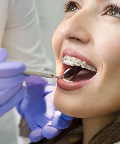 Dentist examining patient receiving adult orthodontics treatment