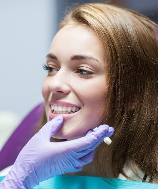 Dentist examining patient's smile after placing dental crowns