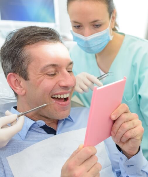 Man looking at smile after dental bridge restoration