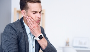 Man in need of T M J therapy holding jaw in pain