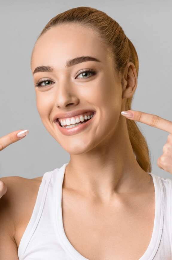 Woman pointing to her smile after porcelain veneers