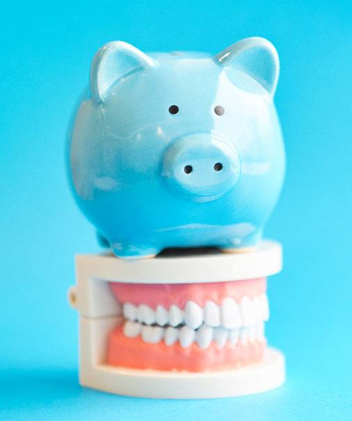 A piggy bank and mouth model, symbolizing the cost of veneers in Newbury Park