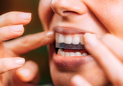 Woman using teeth whitening strips