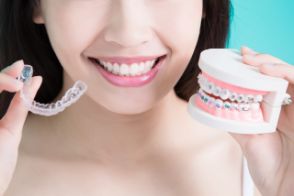 Woman holding Invisalign tray and braces in each hand