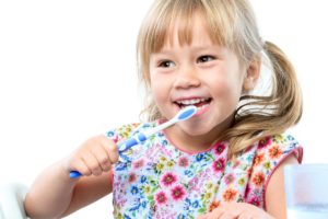 little girl with blond pigtails brushing her teeth