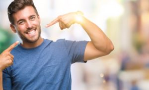 young man pointing to his smile after seeing his cosmetic dentist  