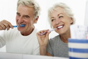 elderly couple following dental hygiene tips by brushing their teeth 