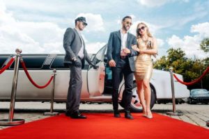 couple getting out of limousine and walking red carpet 